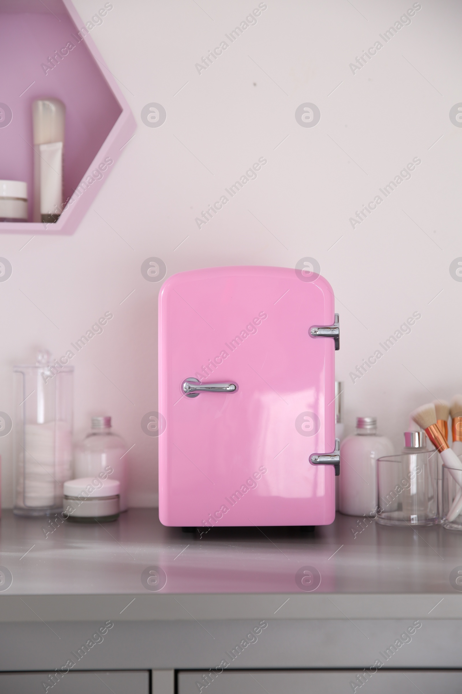 Photo of Cosmetics refrigerator and skin care products on grey vanity table indoors