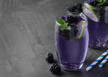 Delicious blackberry lemonade made with soda water on grey table. Space for text