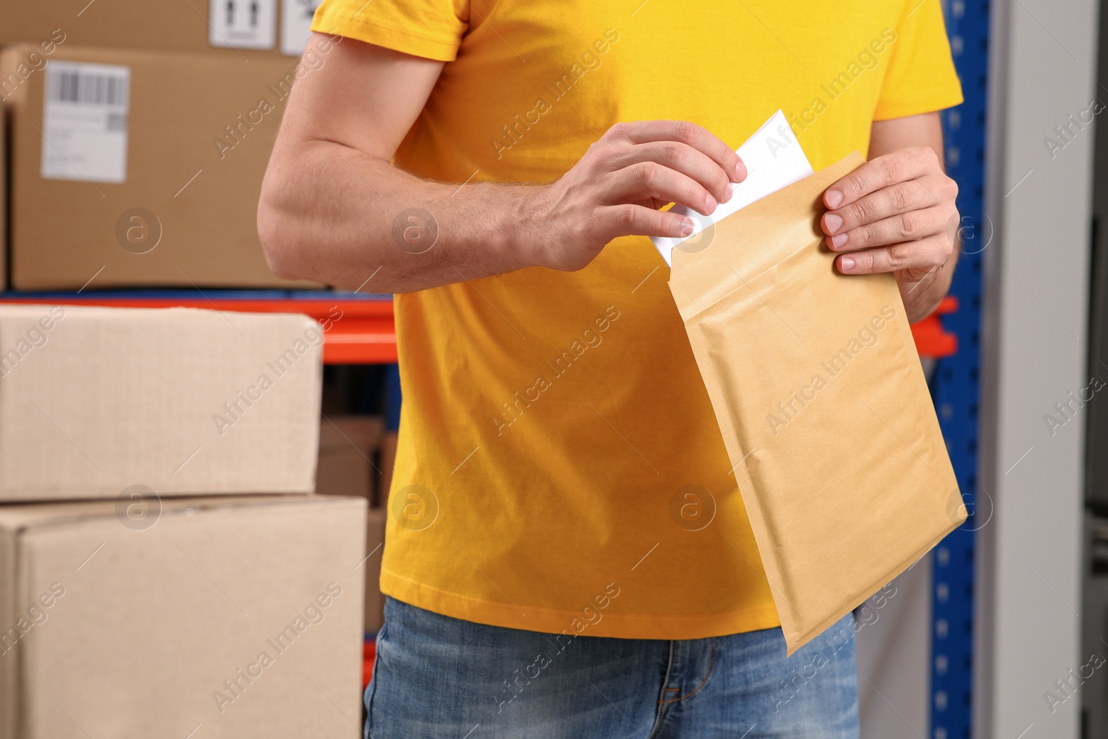 Photo of Post office worker putting envelope into adhesive bag indoors, closeup