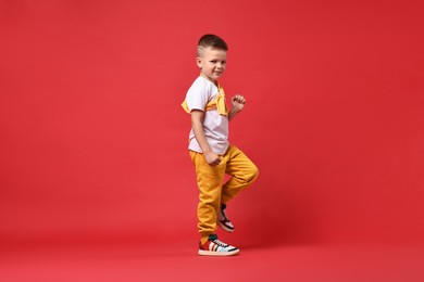 Happy little boy dancing on red background