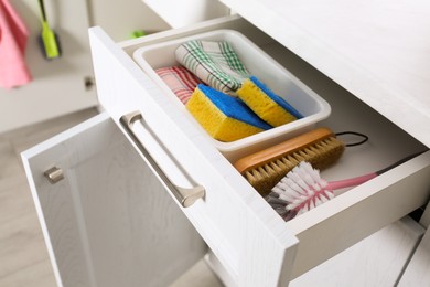 Photo of Different cleaning supplies in open drawer indoors