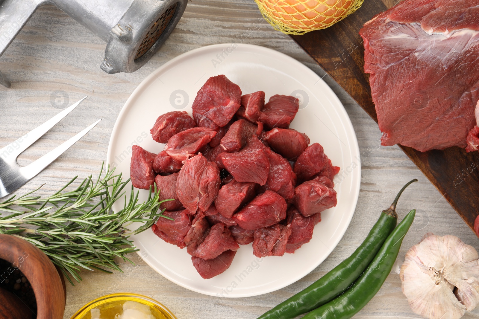 Photo of Pieces of beef and products on white wooden table, flat lay