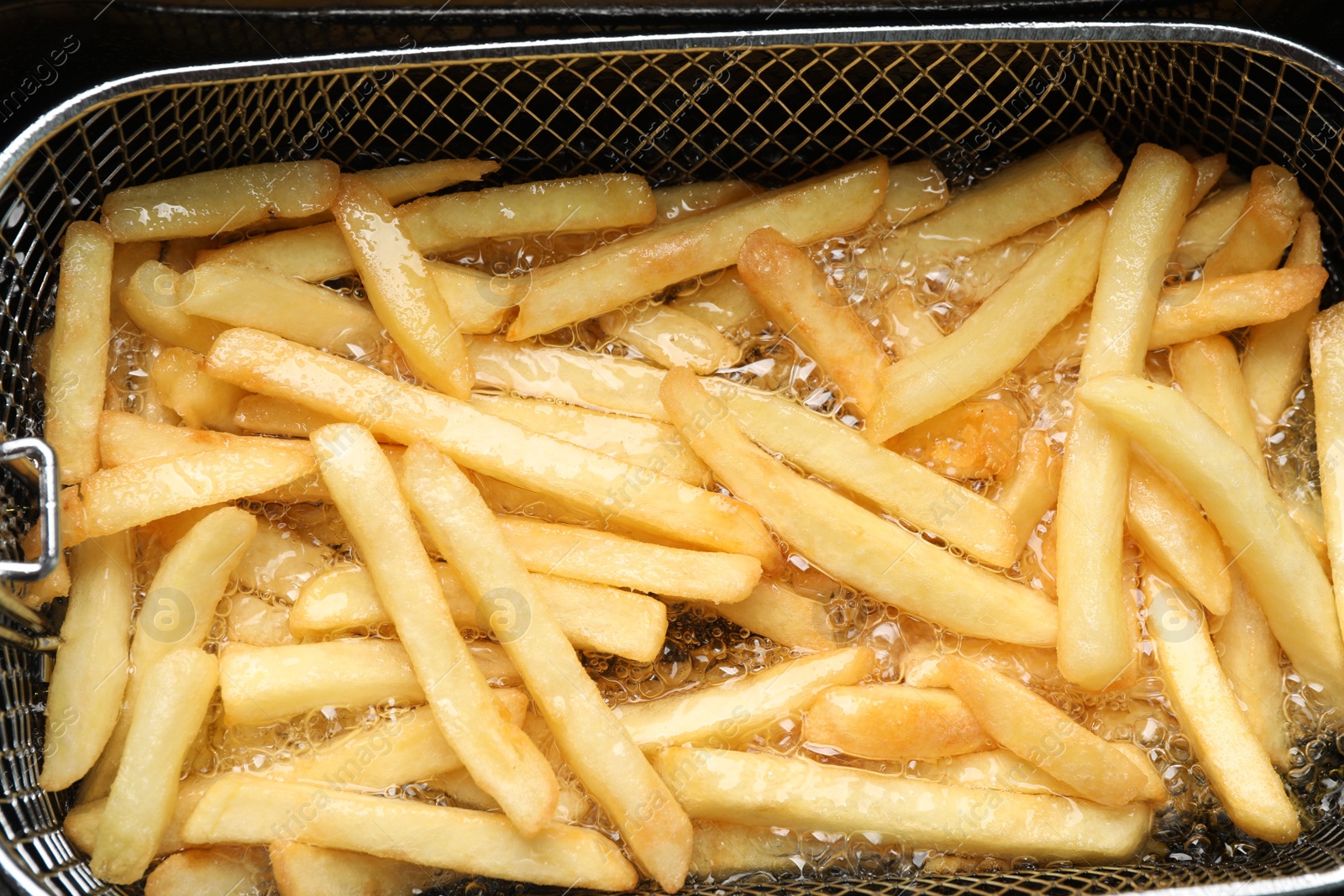 Photo of Cooking delicious french fries in hot oil, closeup