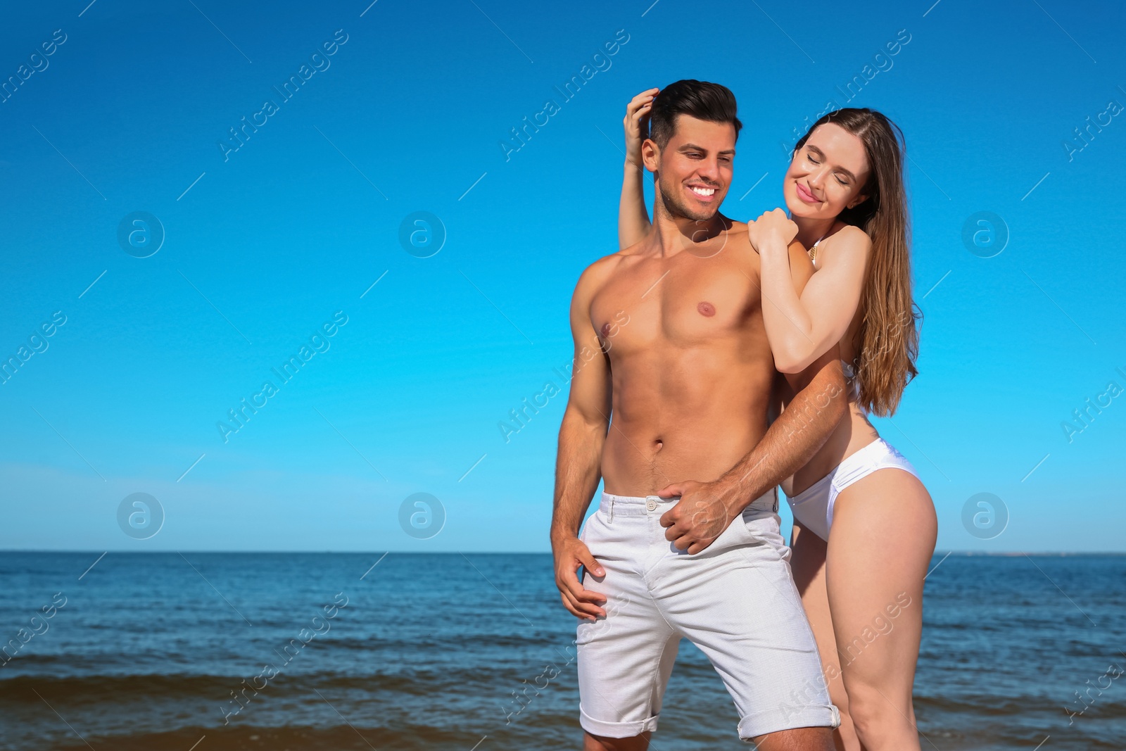 Photo of Woman in bikini and her boyfriend on beach, space for text. Happy couple