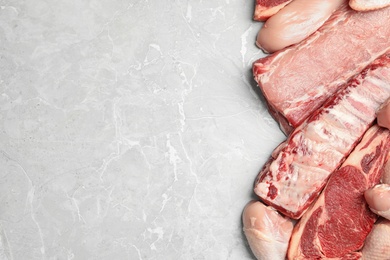 Different types of meat on light grey marble table, flat lay. Space for text