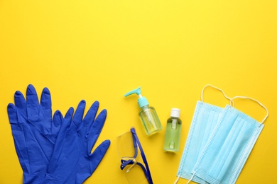 Photo of Flat lay composition with medical gloves, masks and hand sanitizers on yellow background. Space for text