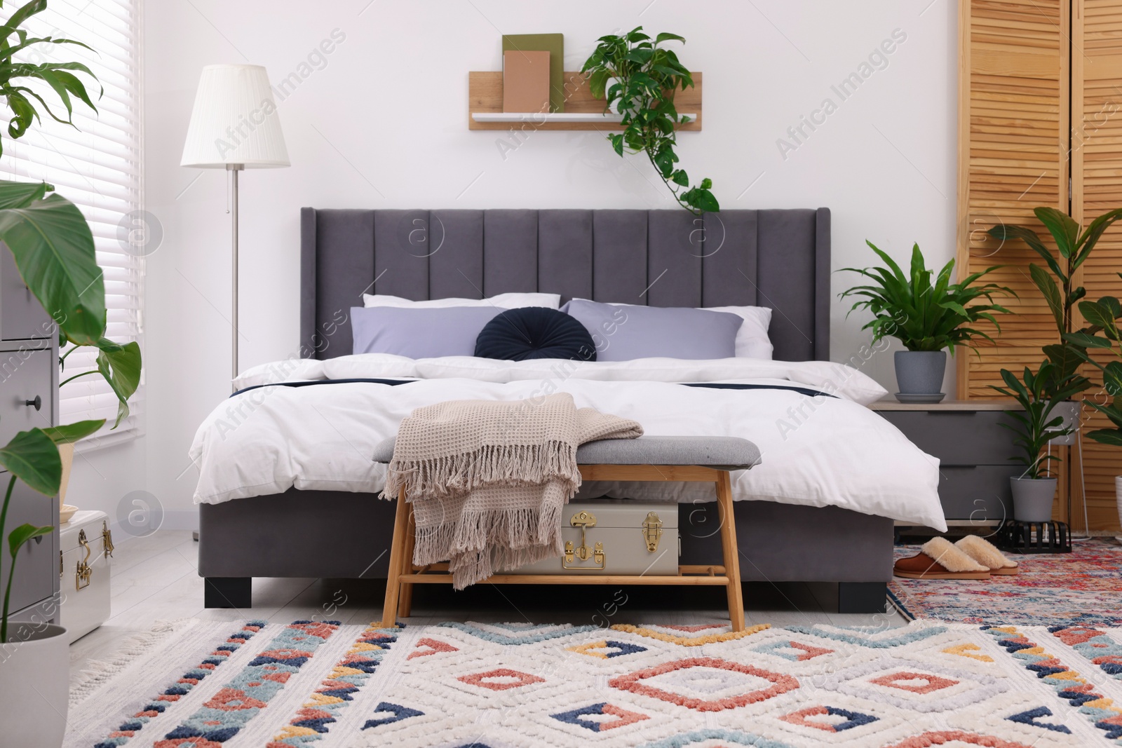 Photo of Stylish bedroom with double bed and beautiful green houseplants. Modern interior