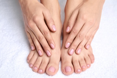 Photo of Woman touching her smooth feet on white towel, closeup. Spa treatment