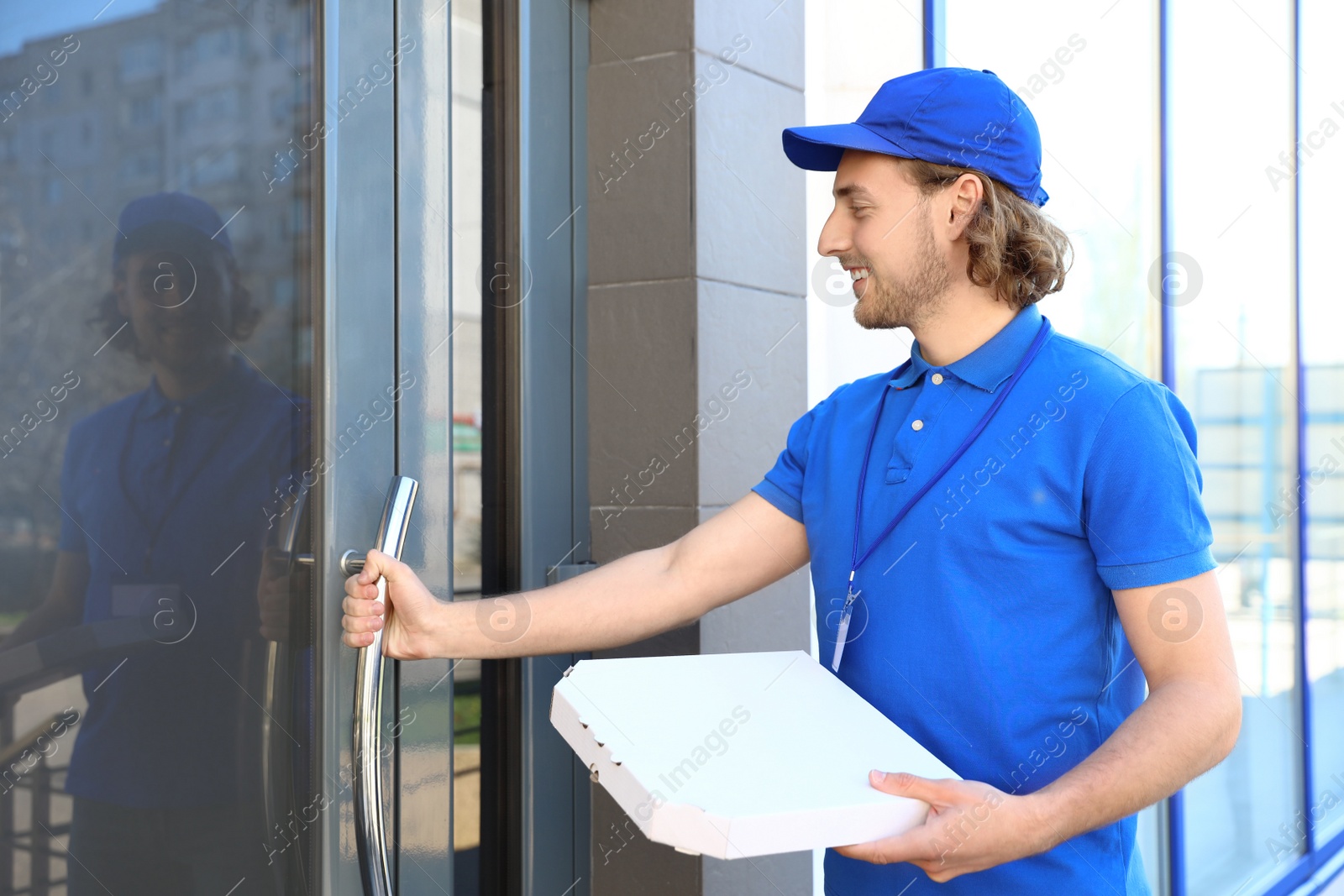 Photo of Male courier with pizza at entrance. Food delivery service