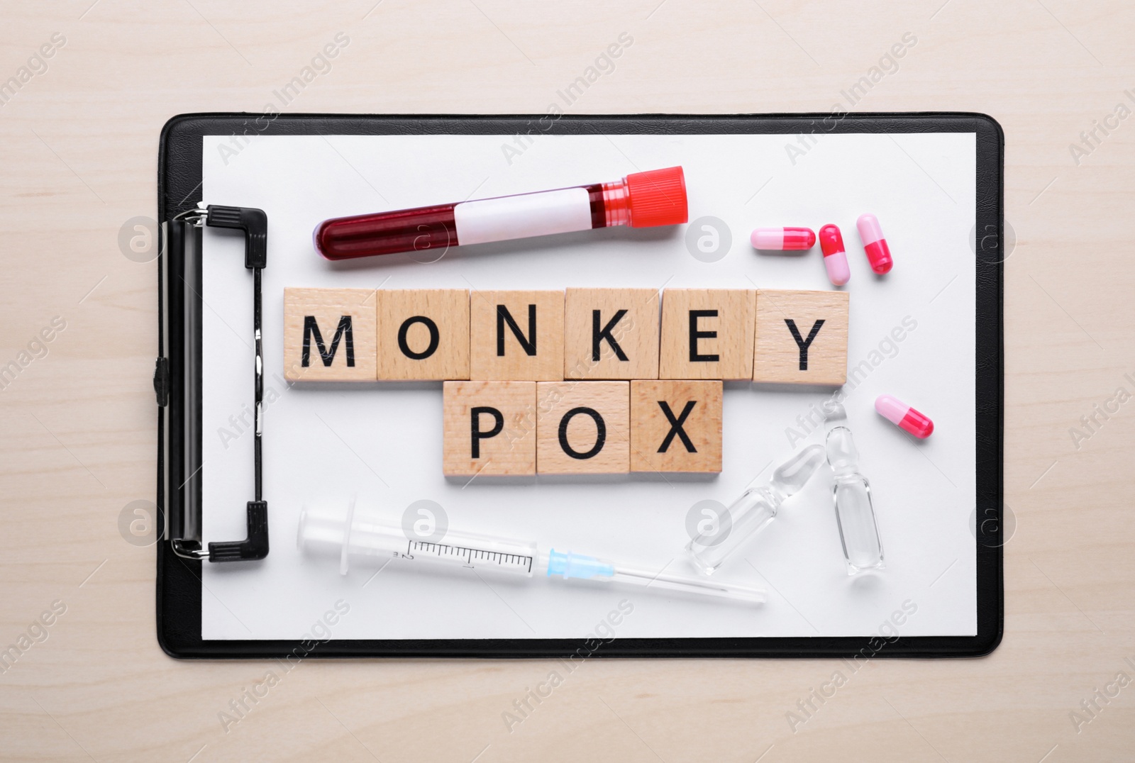 Photo of Flat lay composition with words Monkeypox made of squares and test tube on wooden table