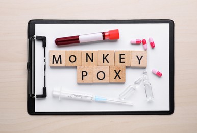 Flat lay composition with words Monkeypox made of squares and test tube on wooden table