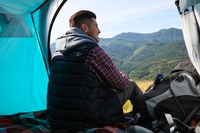 Man inside of camping tent in mountains