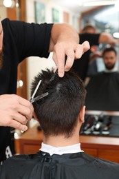 Photo of Professional hairdresser working with client in barbershop, closeup