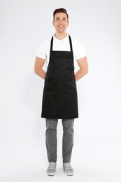 Photo of Full length portrait of handsome waiter in apron on light background