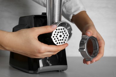 Photo of Woman assembling electric meat grinder at grey table, closeup