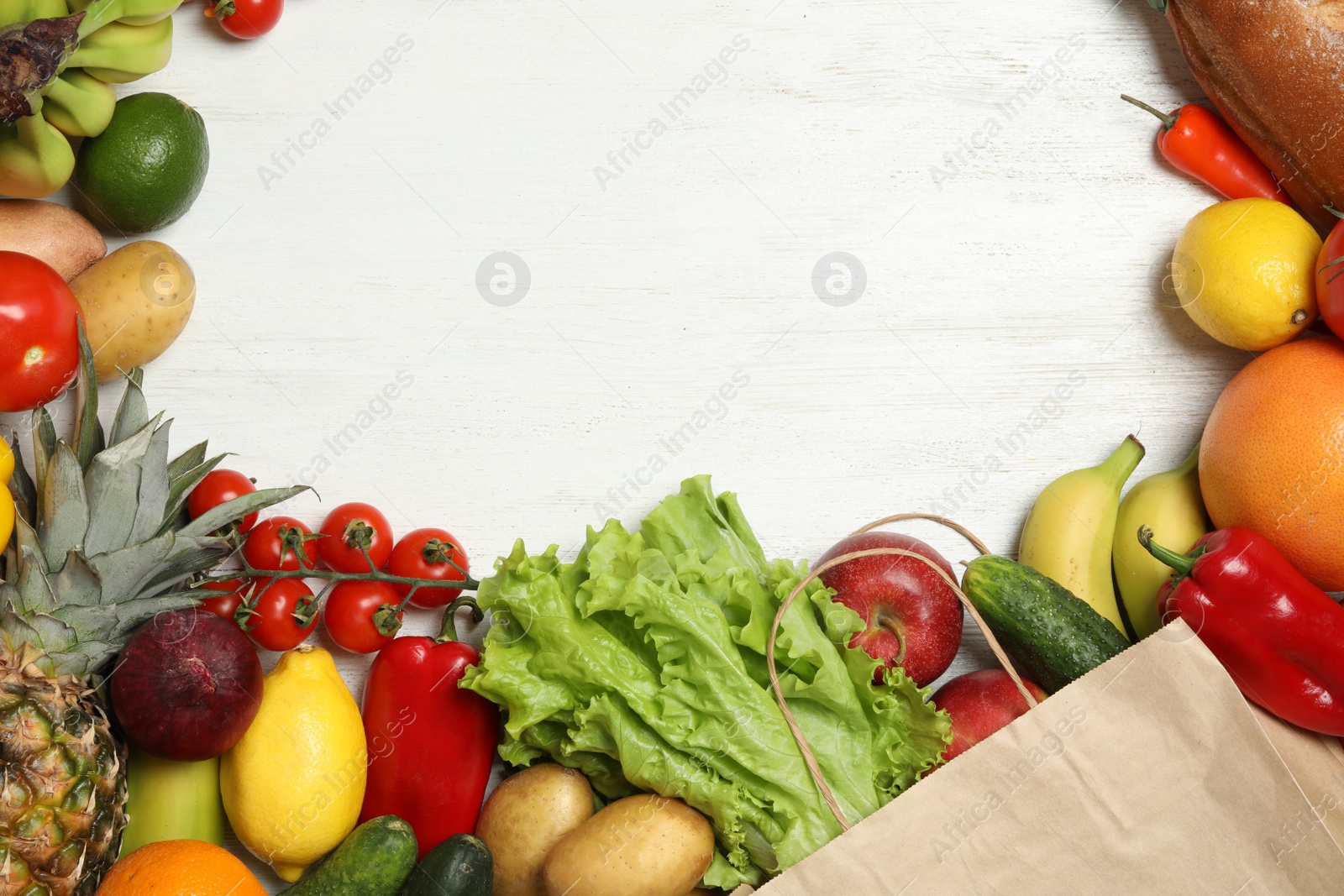 Photo of Frame of paper bag with fresh vegetables and fruits on white wooden background, top view. Space for text