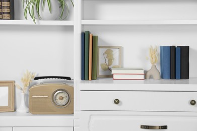 Photo of Hardcover books, decor and vintage radio on shelving unit