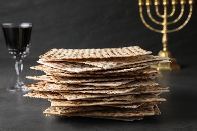 Photo of Stack of traditional matzos near red wine on grey table