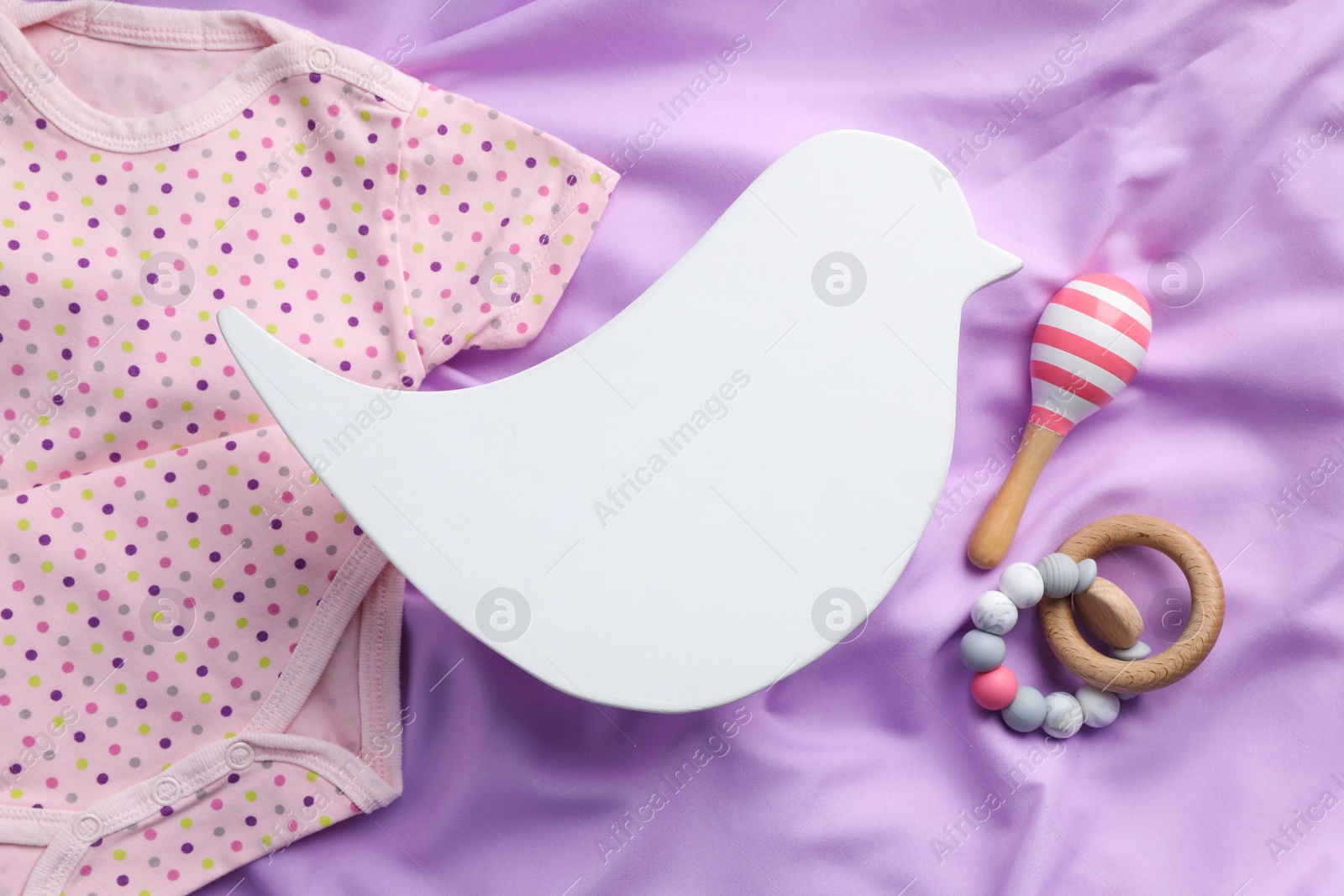 Photo of Flat lay composition with bird shaped child's night lamp on violet fabric