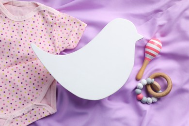 Photo of Flat lay composition with bird shaped child's night lamp on violet fabric