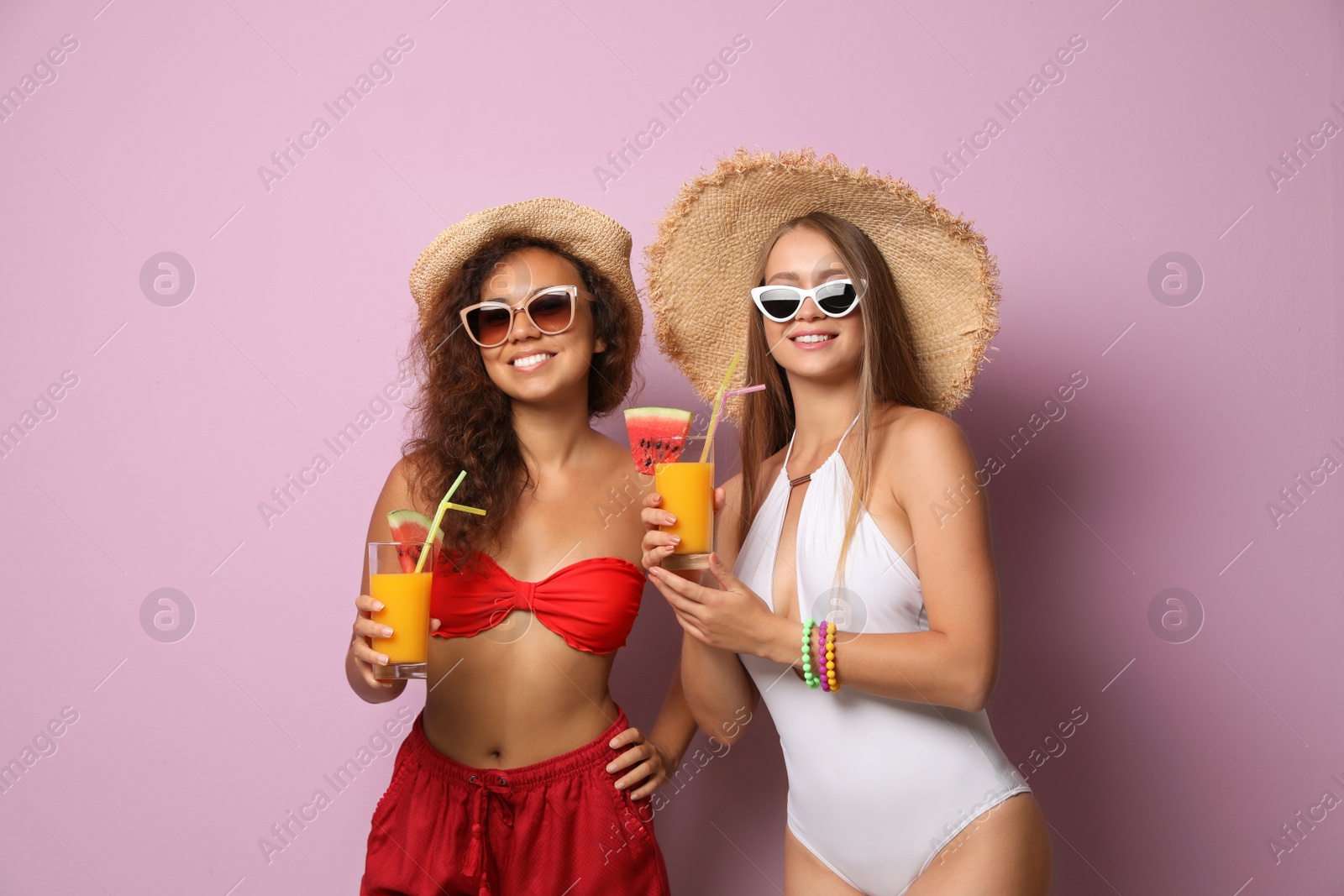 Photo of Beautiful young women in beachwear with cocktails on color background