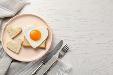 Photo of Heart shaped fried egg served on white wooden table, flat lay. Space for text