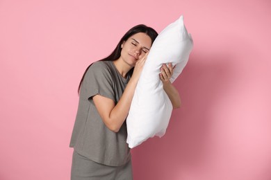 Sleepy young woman with soft pillow on pink background