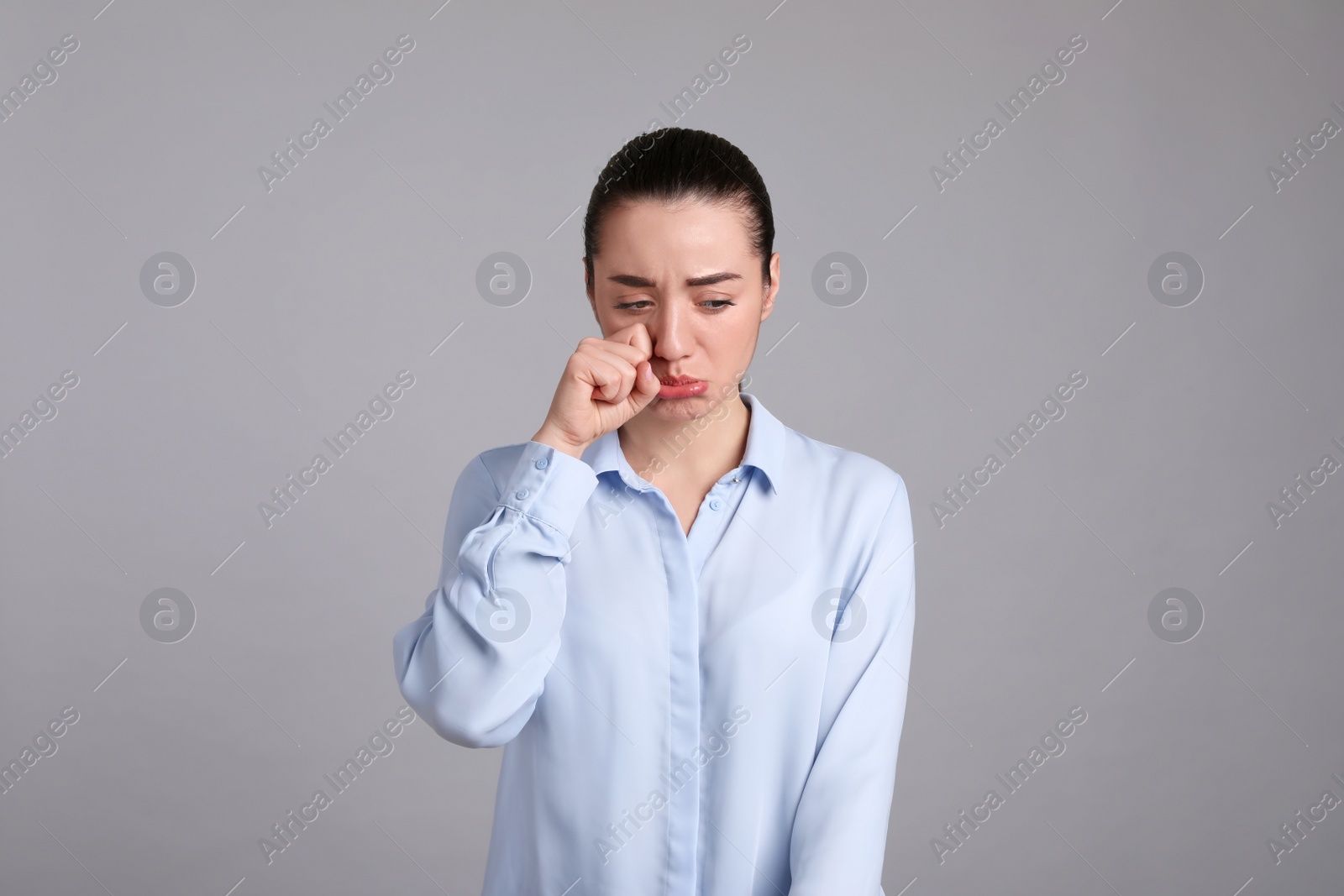 Photo of Portrait of sad young woman on light grey background. Personality concept