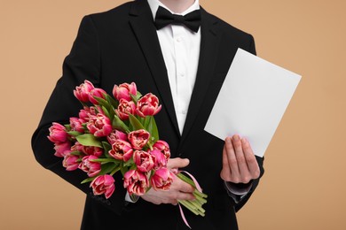 Photo of Man with beautiful bouquet and greeting card on beige background, closeup