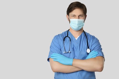 Photo of Doctor or medical assistant (male nurse) with protective mask and stethoscope on light grey background. Space for text