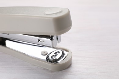 Photo of Beige stapler with staples on light wooden table, closeup. Space for text