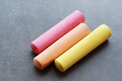 Photo of Colorful chalk sticks on black surface, closeup