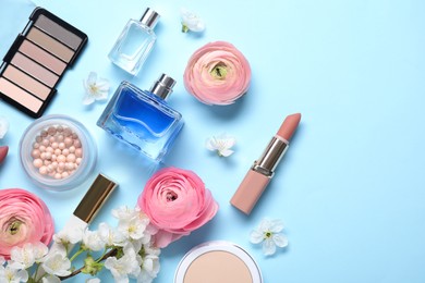 Photo of Flat lay composition with different makeup products and beautiful spring flowers on light blue background, space for text