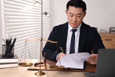 Notary writing notes at wooden table in office