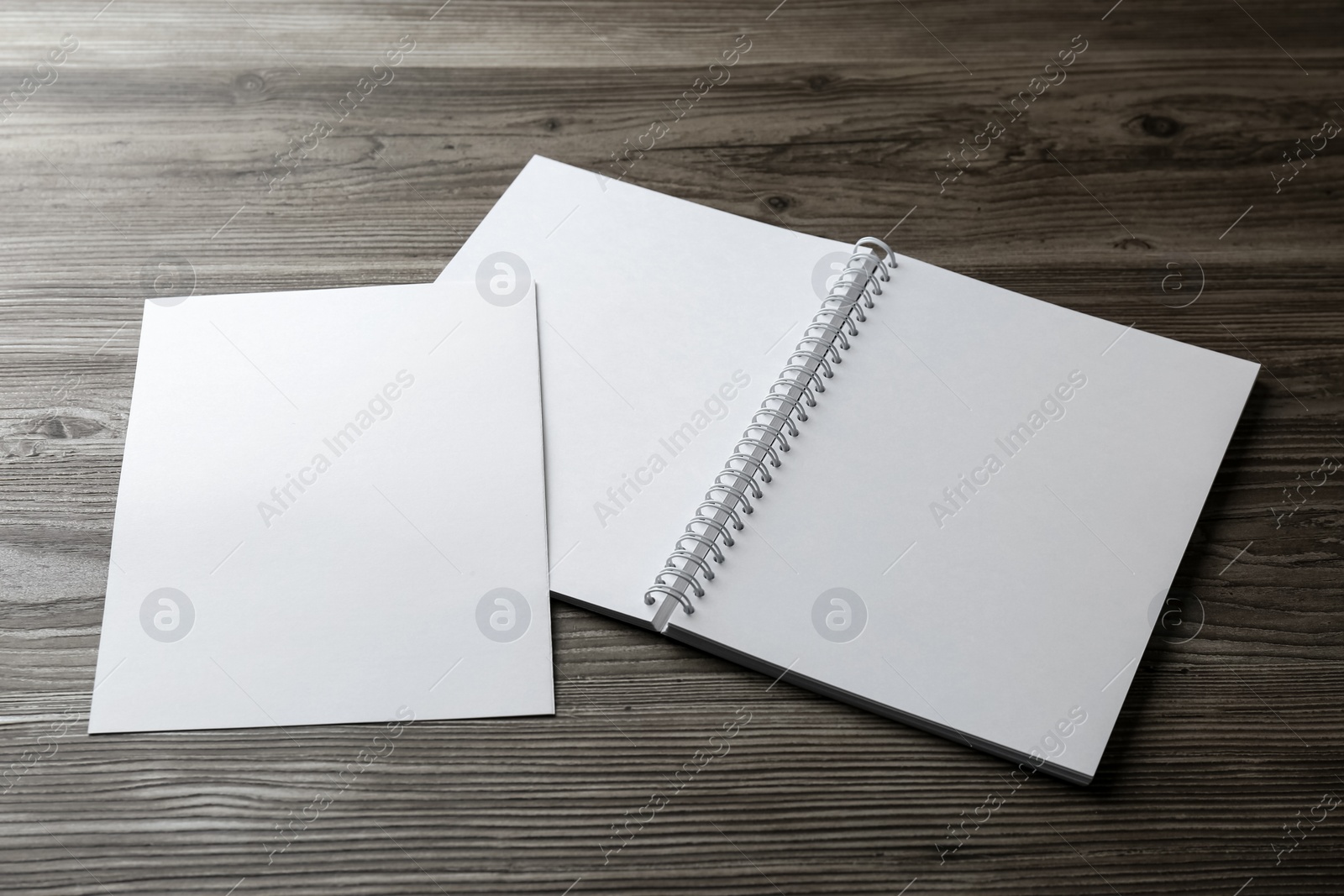 Photo of Sheet of paper and blank brochure on wooden table. Mockup for design