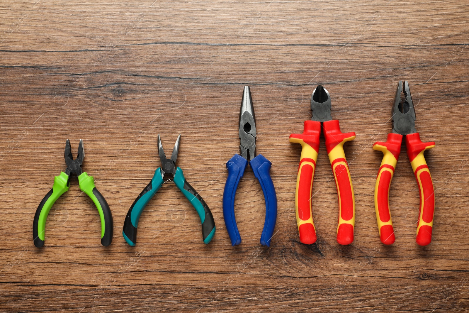 Photo of Different pliers on wooden table, flat lay