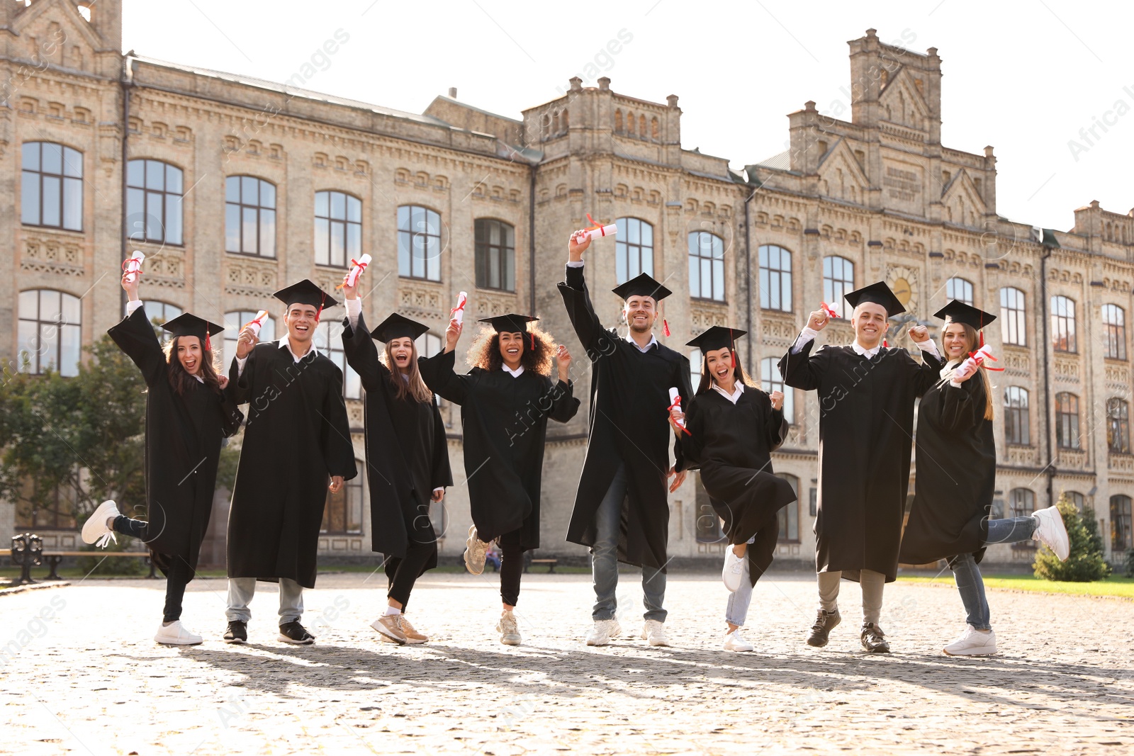 Photo of Happy students with diplomas outdoors. Graduation ceremony