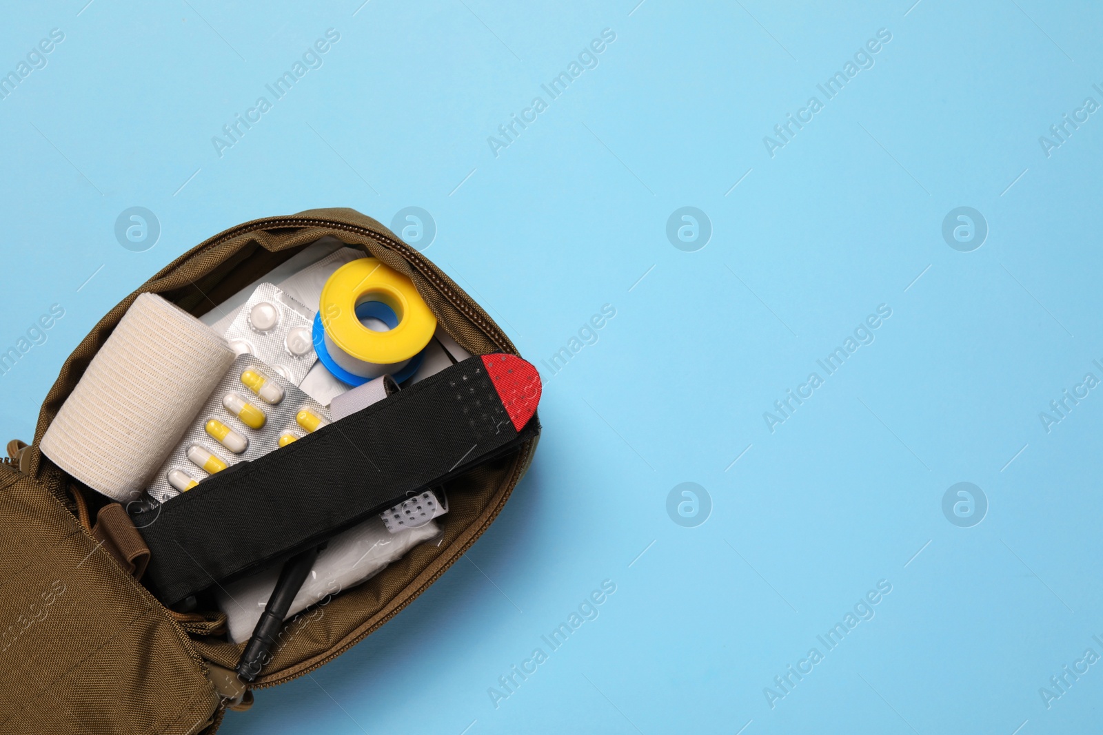 Photo of Military first aid kit on light blue background, top view. Space for text