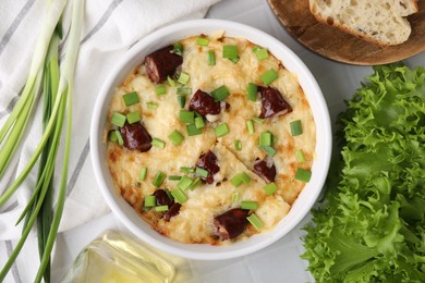 Tasty sausage casserole in baking dish served on white tiled table, flat lay