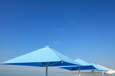 Photo of Bright beach umbrellas against blue sky on sunny day