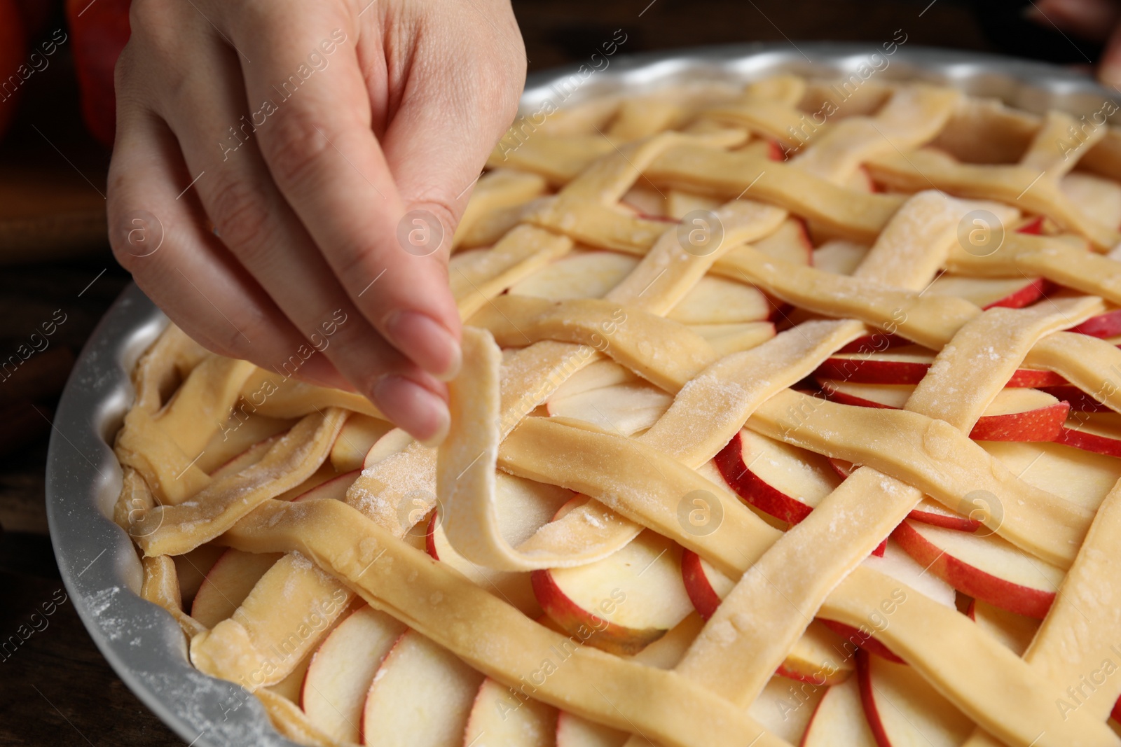 Photo of Woman making lattice top for traditional English apple pie, closeup