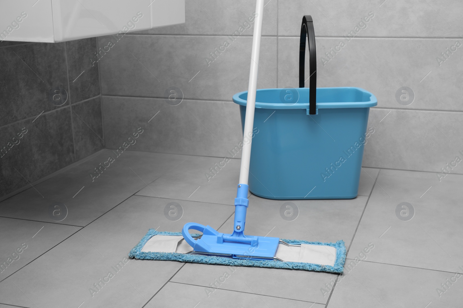 Photo of Mop and bucket on tiled floor in toilet