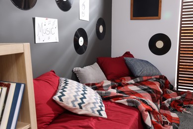 Bed with pillows, posters and vinyl records on wall in teenager's room