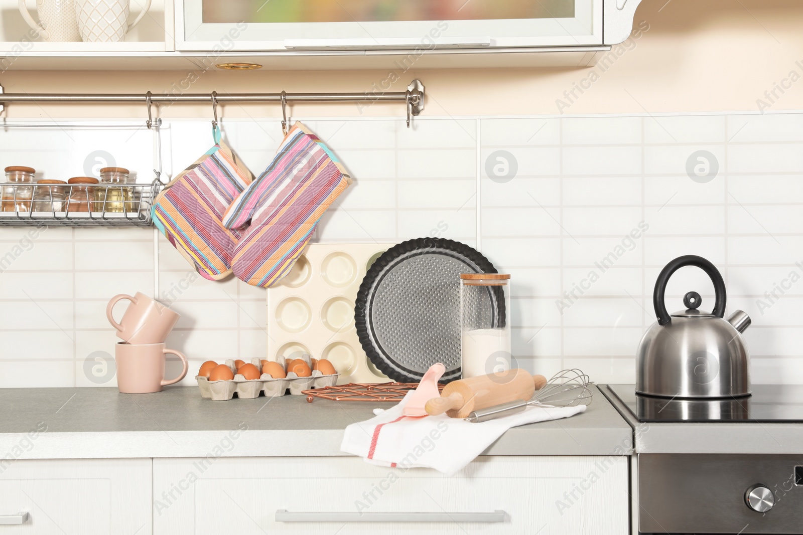 Photo of Set of clean cookware, utensils and products on table in modern kitchen