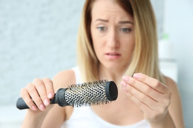 Photo of Young woman with hair loss problem at home