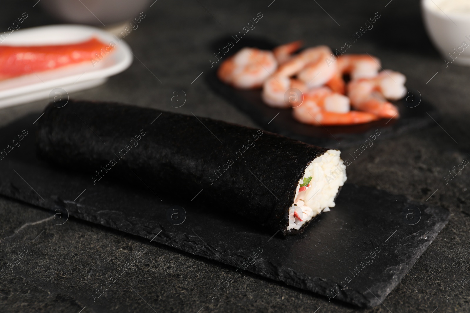 Photo of Tasty sushi roll on dark textured table, closeup