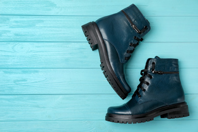 Stylish female boots on light blue wooden table, flat lay. Space for text