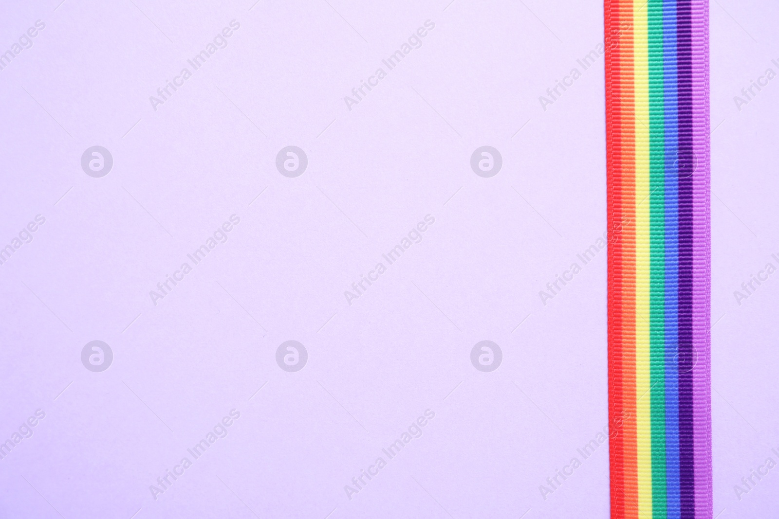 Photo of Bright rainbow ribbon on color background, top view with space for text. Symbol of gay community