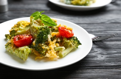 Photo of Tasty broccoli casserole served on black wooden table