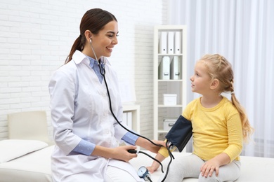 Photo of Little girl visiting doctor in hospital. Measuring blood pressure and checking pulse